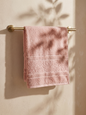Linoa 450 Hudoo in blush pink 100% cotton towel, draped over a rail