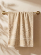 Linoa 550 Reesha Feather in sand 100% cotton towel, draped over a rail